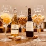 three wine glasses with potato chips, peanuts and popcorn in each of them.